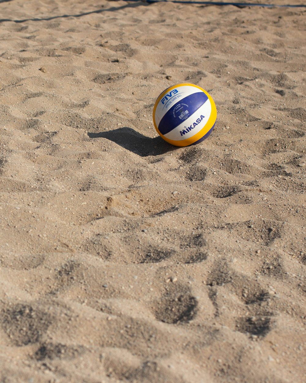 A volleyball resting alone on warm sand