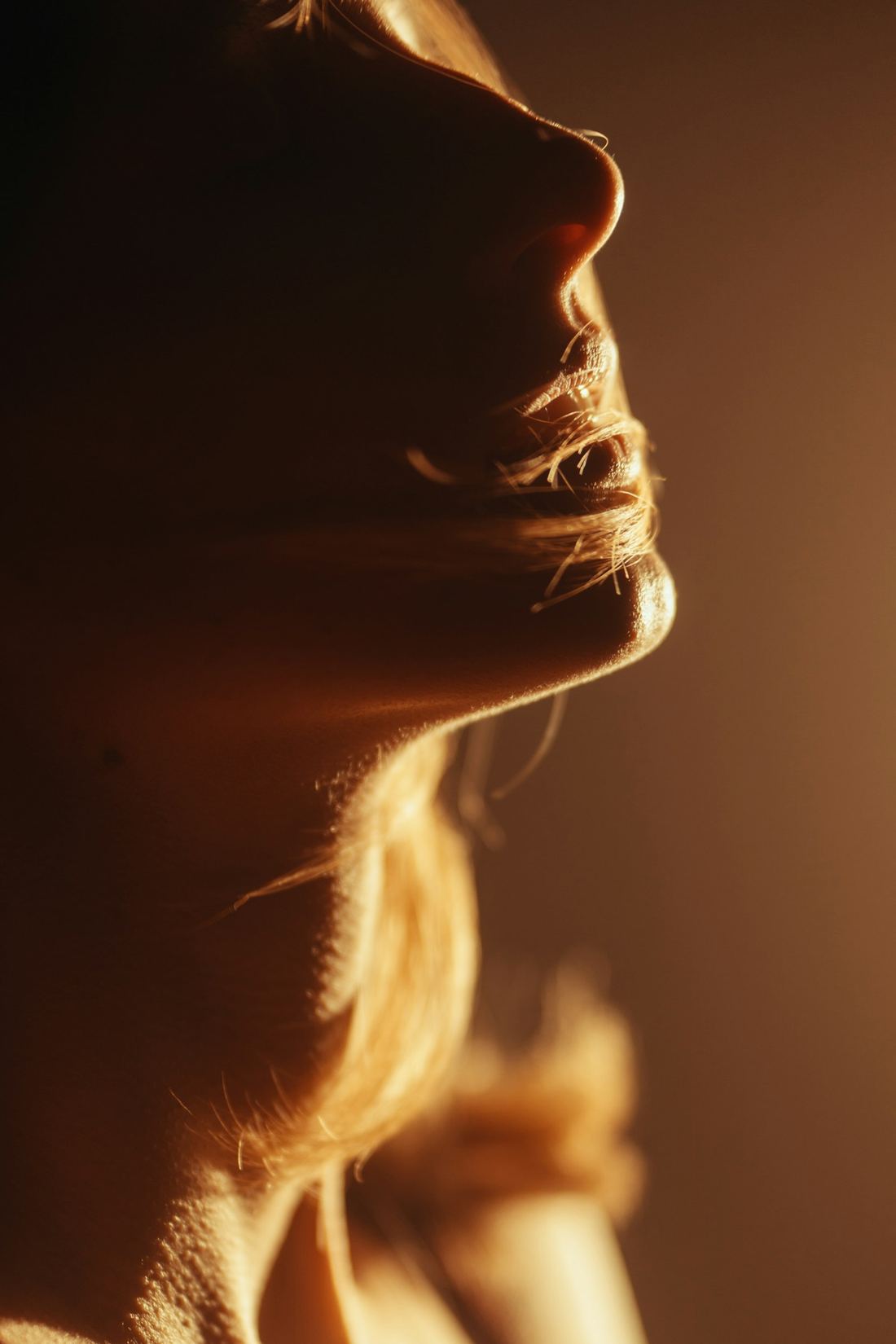 A face tilted upward in warm light, mid-breath