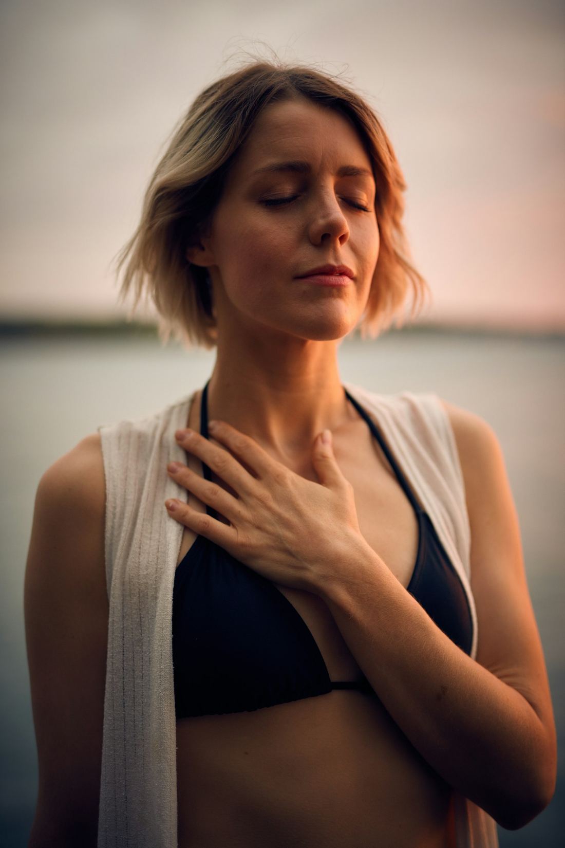 A woman with eyes closed and one hand resting on her chest