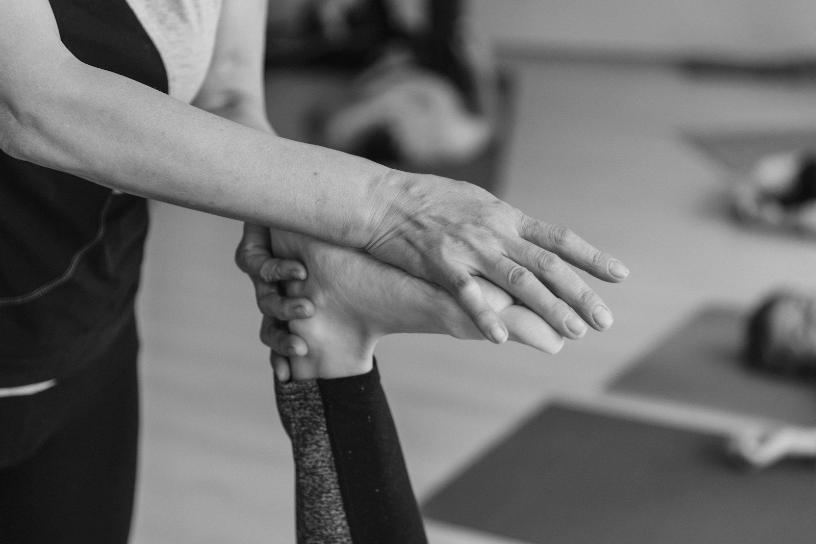 Black and white photograph of a clinician guiding a patient's arm through a movement