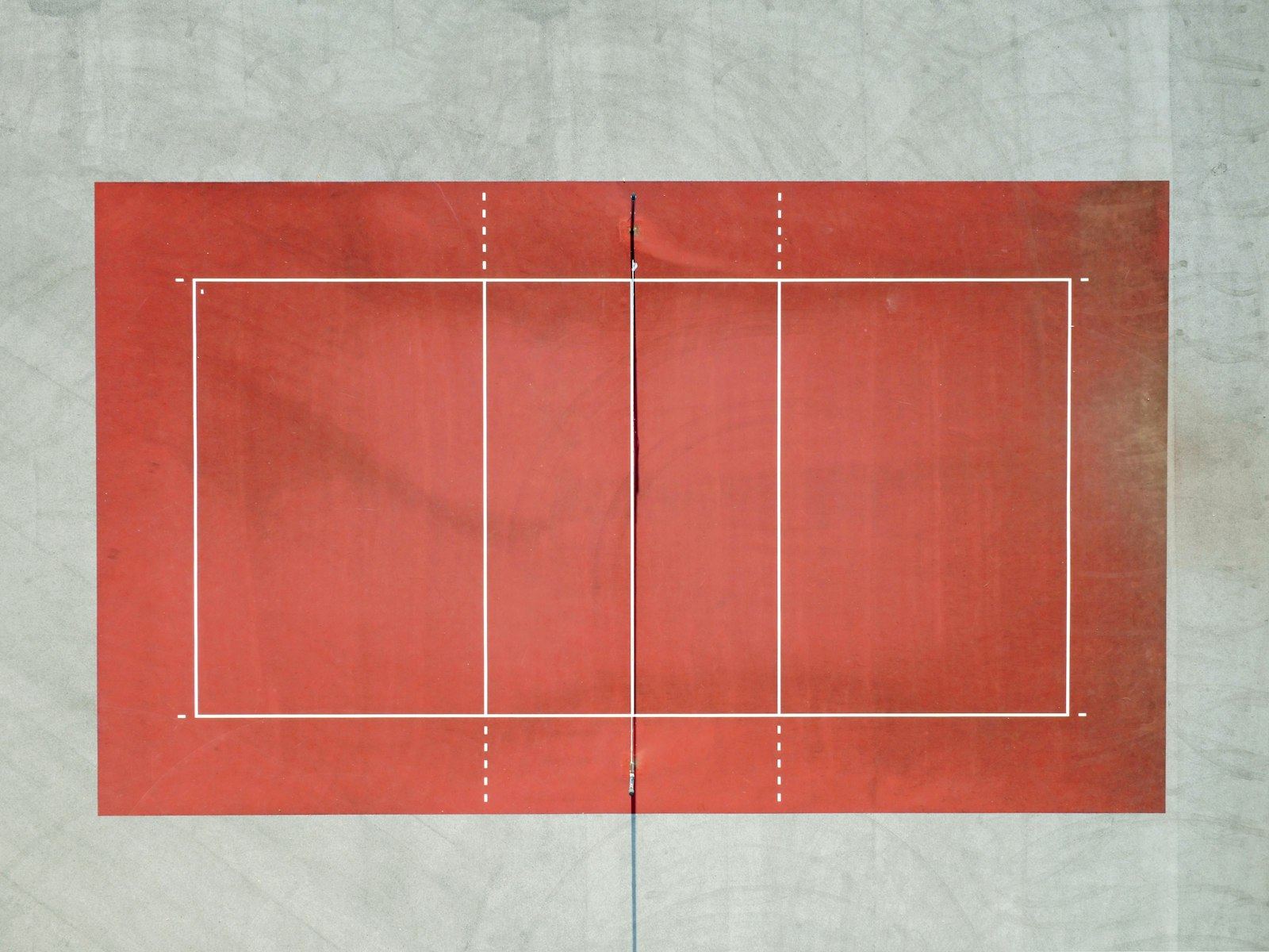 An empty red volleyball court seen from directly above