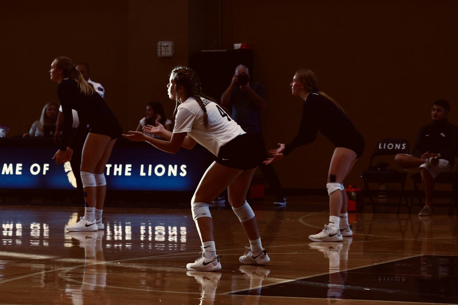 A volleyball team in ready position on a darkened indoor court